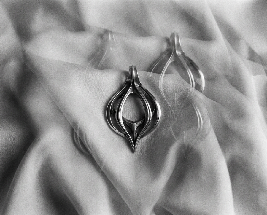 Oxidized biomechanical teardrop pendant suspended on an anchor chain, emphasizing its airy cut-out structure.