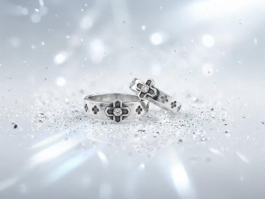 A professional studio photograph of a matching two-piece sterling silver wedding ring set. Both rings feature a prominent, raised Greek-style cross motif in the center, which holds a round, bezel-set white crystal. The interior of the cross arms has a fine, cross-hatched grid texture. Along the sides of the high-polished silver bands are recessed, four-lobed quatrefoil shapes. The rings are presented against a pitch-black background, making the p __etsy:8051335185