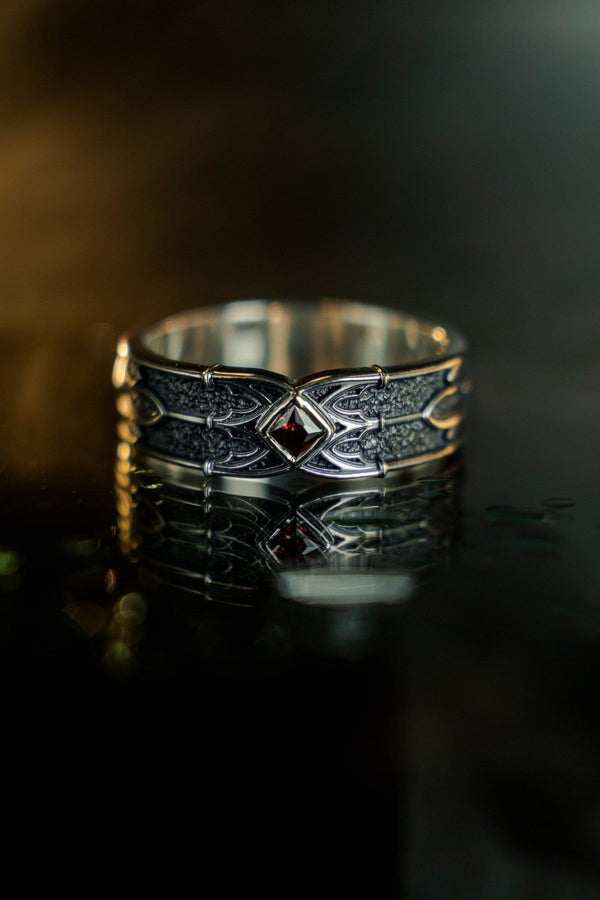 A men’s gothic fantasy ring with a textured darkened surface, silver sculpted lines, and a blood-red center stone. This ring offers a bold mix of elegance and strength, perfect for fans of dark artistry, role-play fashion, or medieval-inspired jewelry. Its sturdy build and eye-catching design make it a meaningful gift for special occasions. __etsy:7131752773