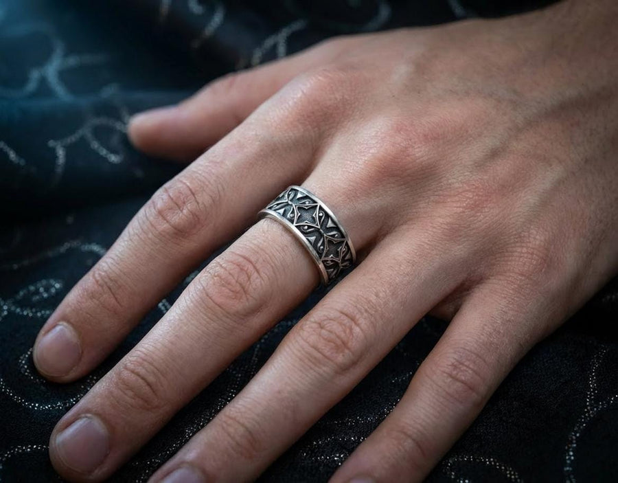 A detailed macro shot of a sterling silver engagement ring. The focal point is a round, honey-colored gemstone (Citrine or Madeira Topaz) set flush into the band. The shank is decorated with a continuous relief pattern of spirals and circles, mimicking the decorative robes found in Gustav Klimt's "Golden Phase" paintings. The silver features an oxidized finish, creating a dark background that makes the polished spirals pop. (etsy image id: 7444385538)