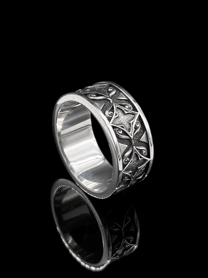 A detailed macro shot of a sterling silver engagement ring. The focal point is a round, honey-colored gemstone (Citrine or Madeira Topaz) set flush into the band. The shank is decorated with a continuous relief pattern of spirals and circles, mimicking the decorative robes found in Gustav Klimt's "Golden Phase" paintings. The silver features an oxidized finish, creating a dark background that makes the polished spirals pop. (etsy image id: 7444385538)