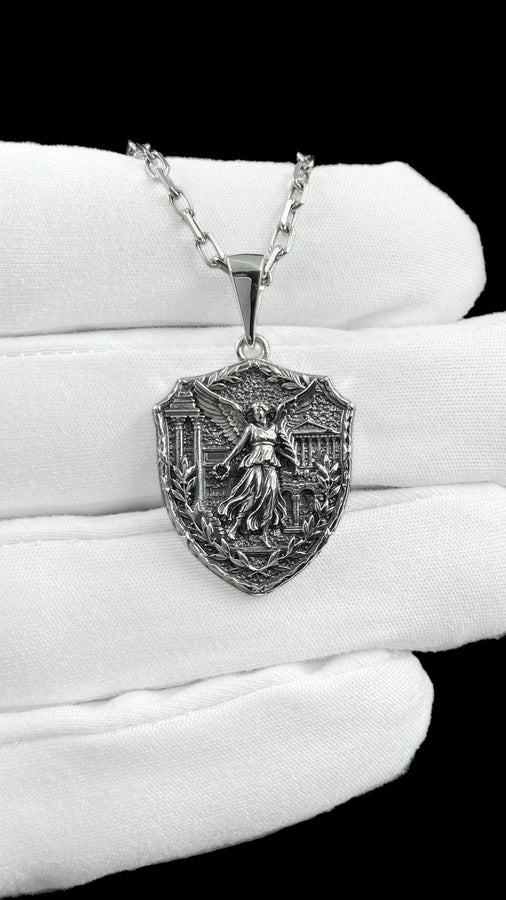 This close-up highlights the masterful texturing of the solid 925 sterling silver casting. The artisan has flawlessly rendered the flowing drape of the goddess's robes and the delicate individual feathers of her outstretched wings. A heavy sulfur oxidation treatment settles deeply into the stippled background, providing a permanent, matte black shadow that defines the sculptural relief and guarantees long-lasting durability. __etsy:8050973927