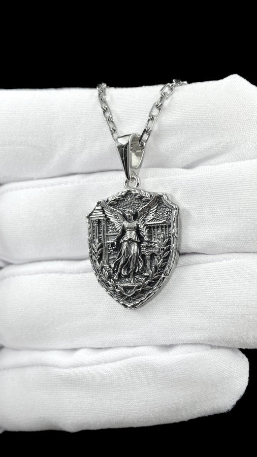 This close-up highlights the masterful texturing of the solid 925 sterling silver casting. The artisan has flawlessly rendered the flowing drape of the goddess's robes and the delicate individual feathers of her outstretched wings. A heavy sulfur oxidation treatment settles deeply into the stippled background, providing a permanent, matte black shadow that defines the sculptural relief and guarantees long-lasting durability. __etsy:8050973927