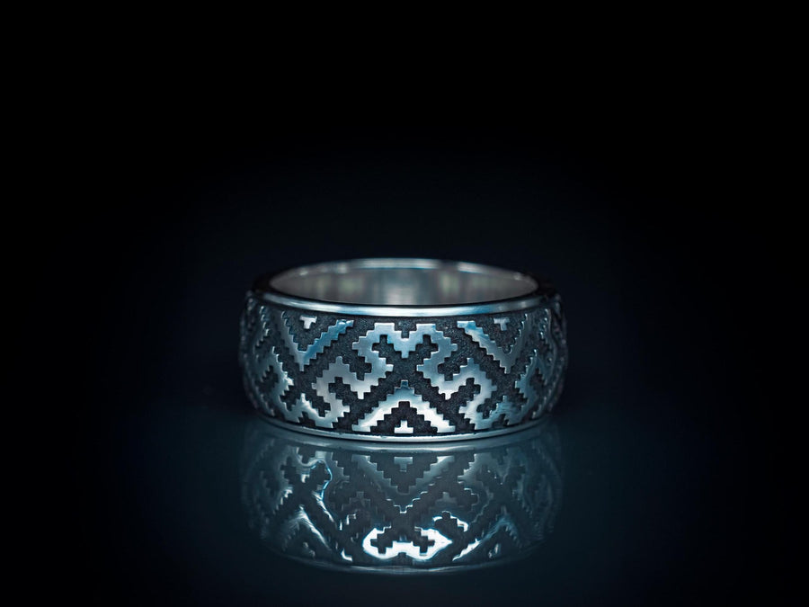 A detailed profile shot of a wide sterling silver ring featuring a repeating "step" or "zig-zag" pattern. The design wraps seamlessly around the entire band. The raised geometric lines are highly polished, catching the light, while the recessed areas are treated with a matte black oxidation. This creates a high-contrast, graphic look similar to a digital pixel pattern or traditional cross-stitch embroidery. (etsy image id: 7438608638)
