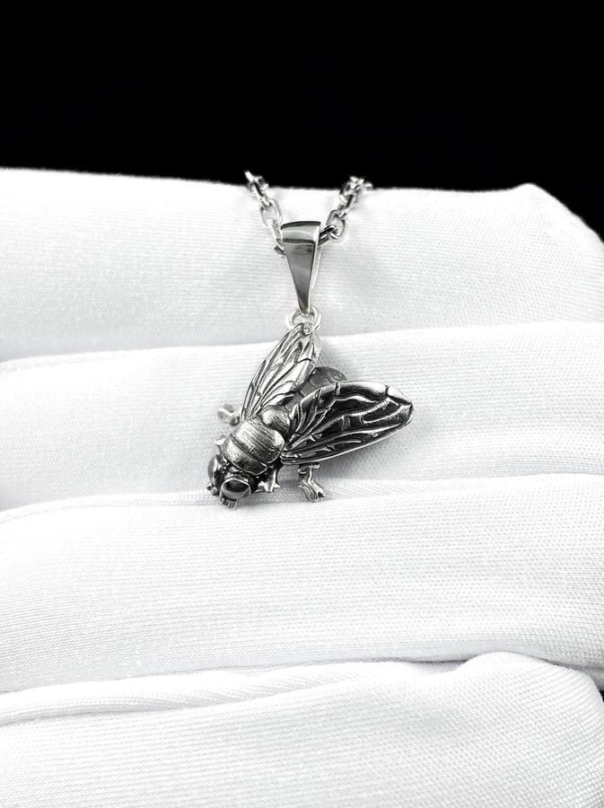 May include: A silver-colored pendant necklace featuring a detailed insect design. The pendant depicts a cicada with intricate wing and body details, suspended from a delicate chain. The necklace is displayed against a white background.