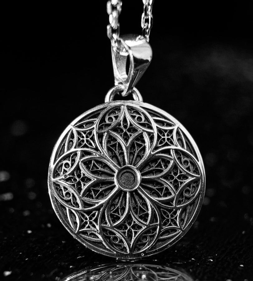 A detailed studio shot of a circular sterling silver pendant resting on a dark, textured slate background. The design is a geometric lattice based on the number four (quatrefoil). Four large teardrop-shaped arches meet in the center, subdivided by finer tracery lines. The raised silver network is polished, contrasting with the matte black oxidation in the negative spaces. __etsy:7446488454