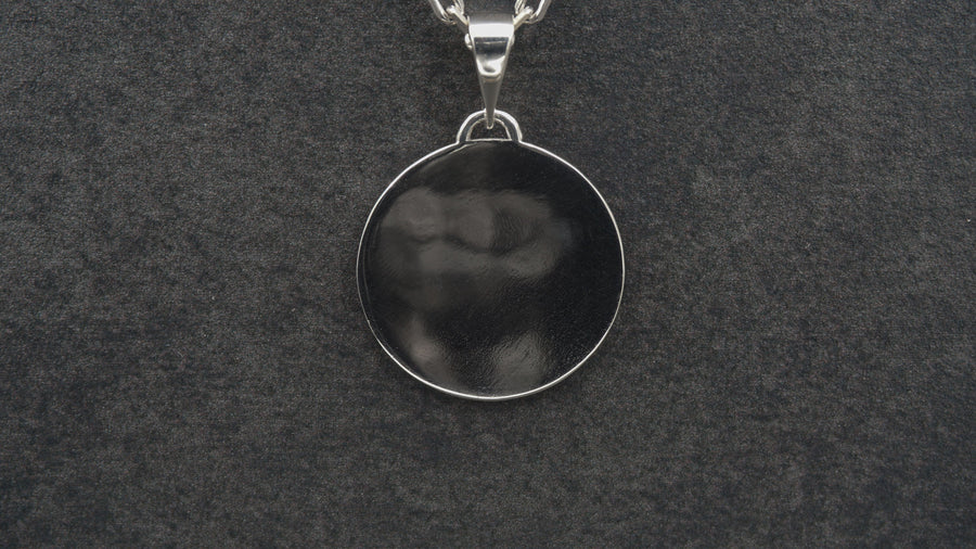 A detailed studio shot of a circular sterling silver pendant resting on a dark, textured slate background. The design is a geometric lattice based on the number four (quatrefoil). Four large teardrop-shaped arches meet in the center, subdivided by finer tracery lines. The raised silver network is polished, contrasting with the matte black oxidation in the negative spaces. __etsy:7446488454
