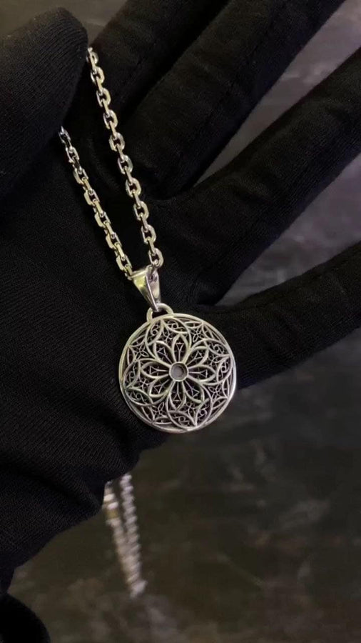 A detailed studio shot of a circular sterling silver pendant resting on a dark, textured slate background. The design is a geometric lattice based on the number four (quatrefoil). Four large teardrop-shaped arches meet in the center, subdivided by finer tracery lines. The raised silver network is polished, contrasting with the matte black oxidation in the negative spaces. __etsy:7446488454
