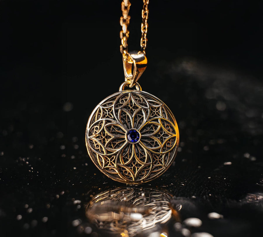 A detailed studio shot of a circular sterling silver pendant resting on a dark, textured slate background. The design is a geometric lattice based on the number four (quatrefoil). Four large teardrop-shaped arches meet in the center, subdivided by finer tracery lines. The raised silver network is polished, contrasting with the matte black oxidation in the negative spaces. __etsy:7446488454