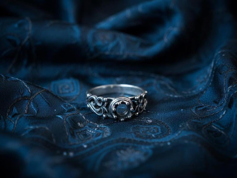 A macro studio shot of a sterling silver solitaire ring. The focal point is a round, clear gemstone (simulated diamond or white sapphire) held in a secure bezel setting. The band is composed of openwork filigree scrolls that swirl around the stone, creating a lace-like effect. The silver features a high-contrast finish: bright, polished vines against a matte black, oxidized background that adds depth and definition. (etsy image id: 7490069229)