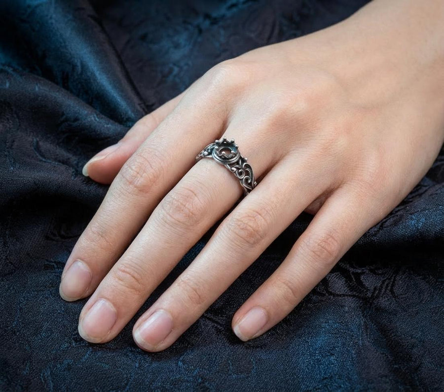 A macro studio shot of a sterling silver solitaire ring. The focal point is a round, clear gemstone (simulated diamond or white sapphire) held in a secure bezel setting. The band is composed of openwork filigree scrolls that swirl around the stone, creating a lace-like effect. The silver features a high-contrast finish: bright, polished vines against a matte black, oxidized background that adds depth and definition. (etsy image id: 7490069229)