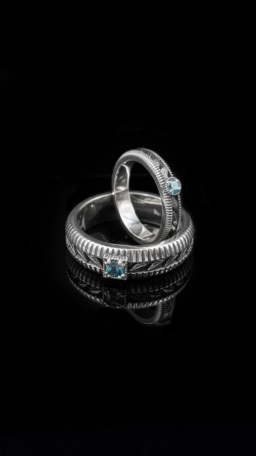 This sterling silver wedding band features intricate Victorian-inspired detailing, including finely engraved laurel leaves that wrap around the entire ring. The ribbed architectural edges create depth and texture, giving the piece an antique character reminiscent of handcrafted heirloom jewelry. Ideal for men or women who appreciate historic design and meaningful symbolism in their wedding band. __etsy:7473345891