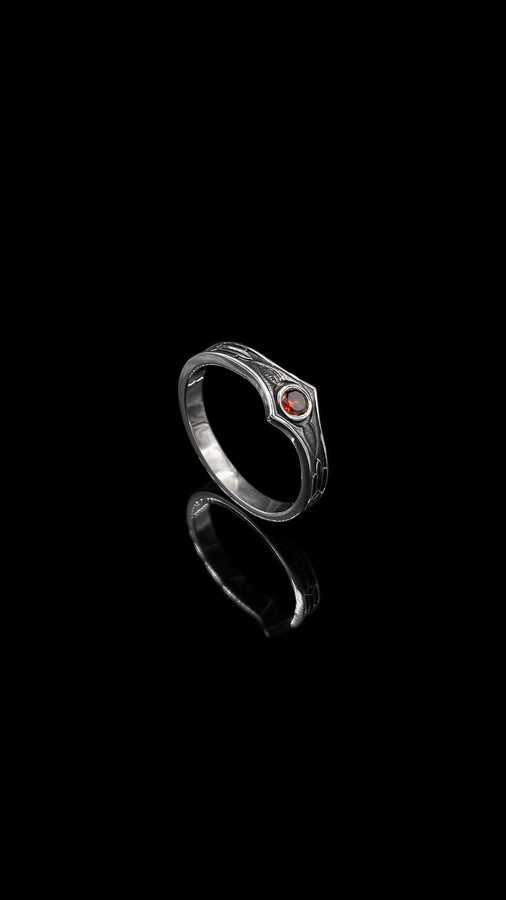 A high-contrast studio shot of a two-piece sterling silver ring set. The foreground features a wide band lying flat, set with a round clear gemstone. Flanking the stone are horizontal, grooved lines resembling arrows or spears. Standing behind it is a narrower engagement-style ring with a matching "lance-tip" shank leading to a central bezel-set white stone. The background is a textured, dark fabric. __etsy:7441122056