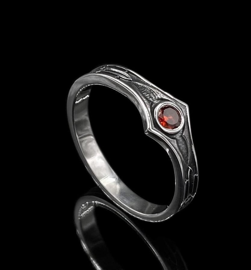 A high-contrast studio shot of a two-piece sterling silver ring set. The foreground features a wide band lying flat, set with a round clear gemstone. Flanking the stone are horizontal, grooved lines resembling arrows or spears. Standing behind it is a narrower engagement-style ring with a matching "lance-tip" shank leading to a central bezel-set white stone. The background is a textured, dark fabric. __etsy:7441122056