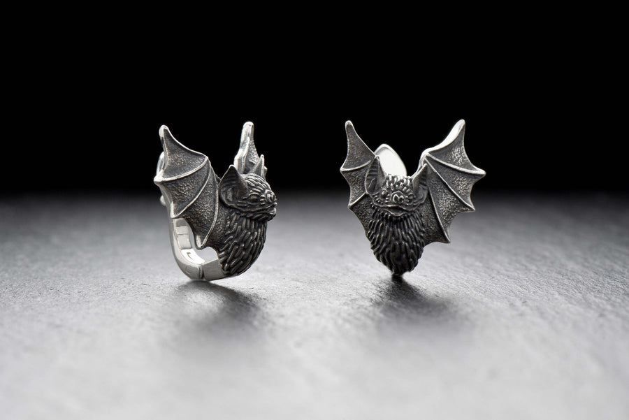 May include: A pair of silver earrings shaped like bats with detailed wings and faces. The hinged plug design allows them to sit securely and closely against the earlobe. Bathed in moody, low-key lighting, these gothic earrings evoke a mystical, nocturnal atmosphere perfect for a dark romance aesthetic. The beautifully detailed silver plug bat earrings capture the essence of vampirecore and whimsigoth fashion. (etsy image id: 5276595997)