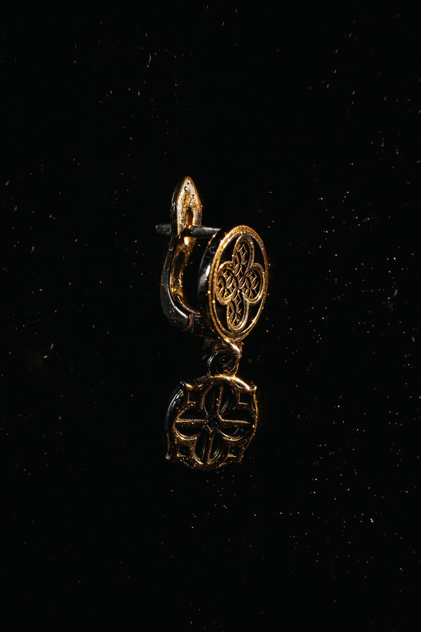 The image highlights the specific textures of the casting. The top stud has a "waffle" or lattice texture inside the quatrefoil lobes, mimicking chainmail or stone carving. The bottom drop is smooth and open, providing a visual counterweight. The 925 sterling silver is treated with an antique patina to enhance the "old world" feel. Modeled as a versatile daily earring, the "coin" size is modest enough for office wear (etsy image id: 5775868859)