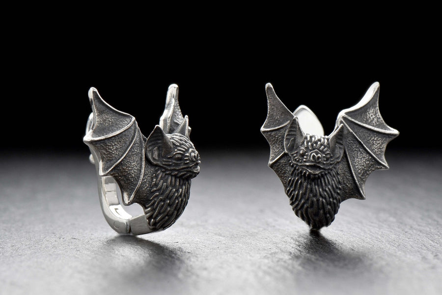 May include: A pair of silver earrings shaped like bats with detailed wings and faces. The hinged plug design allows them to sit securely and closely against the earlobe. Bathed in moody, low-key lighting, these gothic earrings evoke a mystical, nocturnal atmosphere perfect for a dark romance aesthetic. The beautifully detailed silver plug bat earrings capture the essence of vampirecore and whimsigoth fashion. (etsy image id: 5276595997)