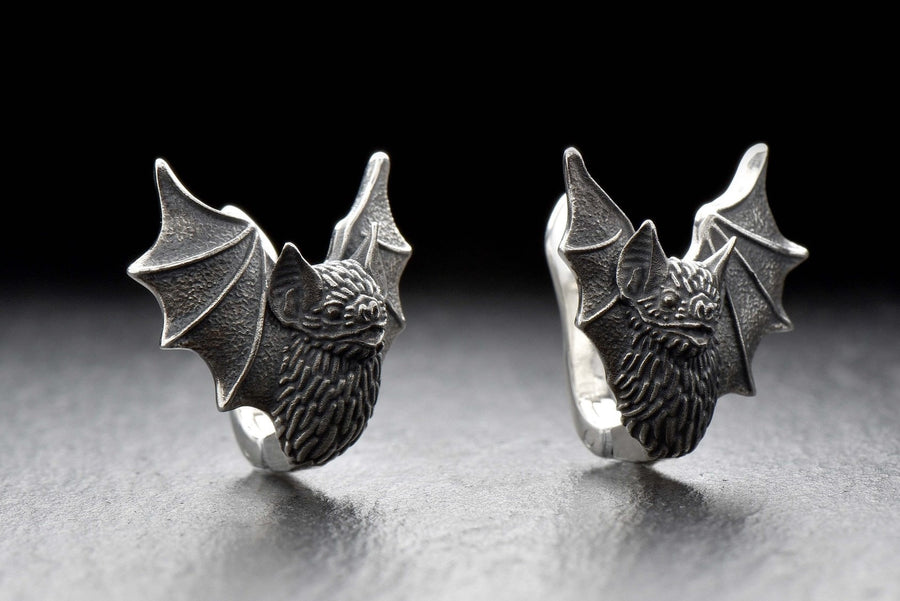 May include: A pair of silver earrings shaped like bats with detailed wings and faces. The hinged plug design allows them to sit securely and closely against the earlobe. Bathed in moody, low-key lighting, these gothic earrings evoke a mystical, nocturnal atmosphere perfect for a dark romance aesthetic. The beautifully detailed silver plug bat earrings capture the essence of vampirecore and whimsigoth fashion. (etsy image id: 5276595997)