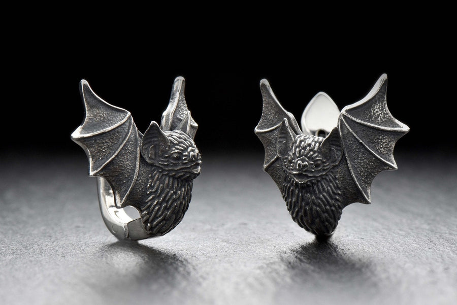 May include: A pair of silver earrings shaped like bats with detailed wings and faces. The hinged plug design allows them to sit securely and closely against the earlobe. Bathed in moody, low-key lighting, these gothic earrings evoke a mystical, nocturnal atmosphere perfect for a dark romance aesthetic. The beautifully detailed silver plug bat earrings capture the essence of vampirecore and whimsigoth fashion. (etsy image id: 5276595997)
