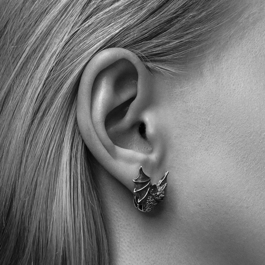 May include: A pair of silver earrings shaped like bats with detailed wings and faces. The hinged plug design allows them to sit securely and closely against the earlobe. Bathed in moody, low-key lighting, these gothic earrings evoke a mystical, nocturnal atmosphere perfect for a dark romance aesthetic. The beautifully detailed silver plug bat earrings capture the essence of vampirecore and whimsigoth fashion. (etsy image id: 5276595997)