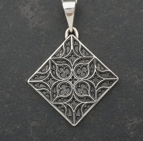 A detailed studio shot of a diamond-shaped (lozenge) sterling silver pendant hanging vertically. The design features intricate "curvilinear" Gothic tracery—four teardrop shapes meeting in the center to form a cross or quatrefoil. The raised lines are polished bright silver, while the negative space behind them is heavily oxidized to a matte black, creating a high-contrast architectural look. (etsy image id: 7494090955)