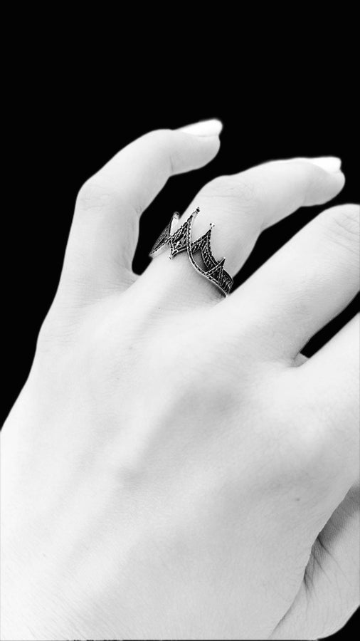 statement ring,	silver ring,	rare ring, gothic architecture,	goth ornament,	gothic window, The image highlights the depth of the casting. The 925 sterling silver features two distinct textures: the smooth, reflective structural lines and the gritty, matte "chainmail" texture within the arches. The oxidation gives the ring an antique patina, making it look like a forged artifact rather than a stamped piece of metal. (etsy image id: 7028750895)