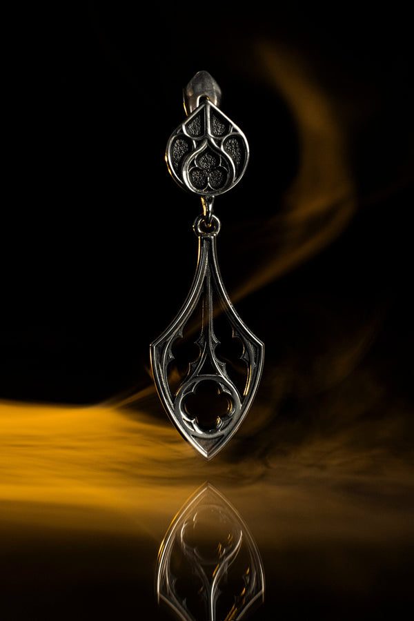 Embrace the dark appeal of gothic fashion with our Sterling Gothic Earrings. Each pair is exquisitely crafted in a gothic style, bringing a touch of mystery and romance to your look. An ideal choice for those who appreciate dark shades of elegance. The image highlights the high-contrast finish of the 925 sterling silver. The "relief" casting gives the tracery lines a three-dimensional quality, mimicking carved stone. (etsy image id: 6150699379)