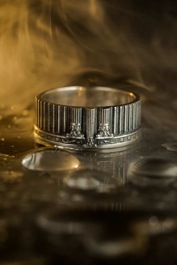 This sterling silver ring set features bold architectural column details with finely carved fluting and ornate capital motifs. The design draws inspiration from ancient Greek and Roman structures, offering a sculptural aesthetic that feels elegant and timeless. Ideal for wedding sets or collectors of detailed art jewelry, the polished silver contrasts beautifully with the deep engraved textures.
