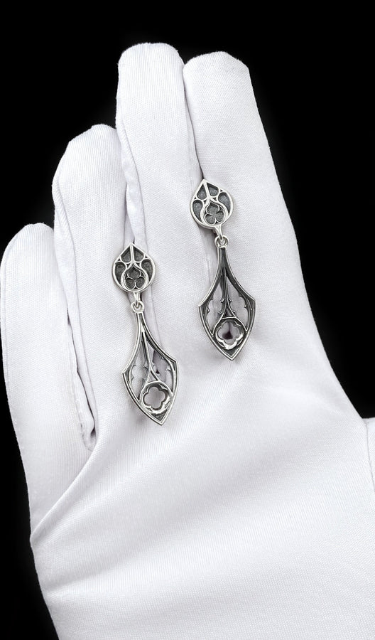 Embrace the dark appeal of gothic fashion with our Sterling Gothic Earrings. Each pair is exquisitely crafted in a gothic style, bringing a touch of mystery and romance to your look. An ideal choice for those who appreciate dark shades of elegance. The image highlights the high-contrast finish of the 925 sterling silver. The "relief" casting gives the tracery lines a three-dimensional quality, mimicking carved stone. (etsy image id: 6150699379)