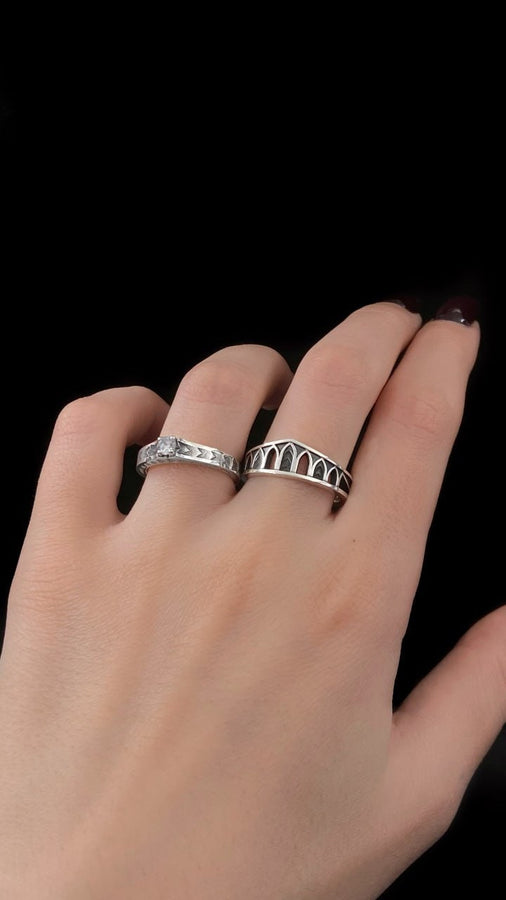 A professional studio photograph of a matching two-piece sterling silver wedding ring set. Both rings feature a prominent, raised Greek-style cross motif in the center, which holds a round, bezel-set white crystal. The interior of the cross arms has a fine, cross-hatched grid texture. Along the sides of the high-polished silver bands are recessed, four-lobed quatrefoil shapes. The rings are presented against a pitch-black background, making the p __etsy:8051335185