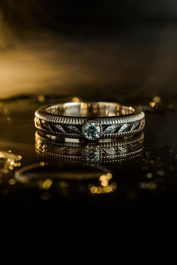 A nature-inspired silver wedding ring featuring raised leaf motifs and a shimmering round gemstone set in the center. The Art Nouveau style is expressed through smooth curves and organic detailing along the band. Ideal for brides or grooms who appreciate delicate plant symbolism, handcrafted jewelry, and an elegant blend of vintage and contemporary design elements in their wedding set. (etsy image id: 6300134508)