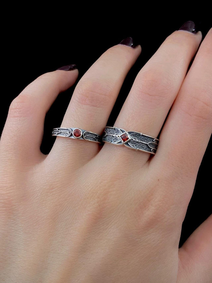 This gothic sterling silver ring features a vivid red garnet set in a detailed medieval-inspired band with darkened textures and graceful, pointed motifs. Designed for lovers of fantasy, gothic fashion, and artisan jewelry, it offers an elegant yet dramatic look. Perfect as a unique wedding band, engagement ring, or statement piece for anyone drawn to symbolic and timeless gothic style. (etsy image id: 7425901470)