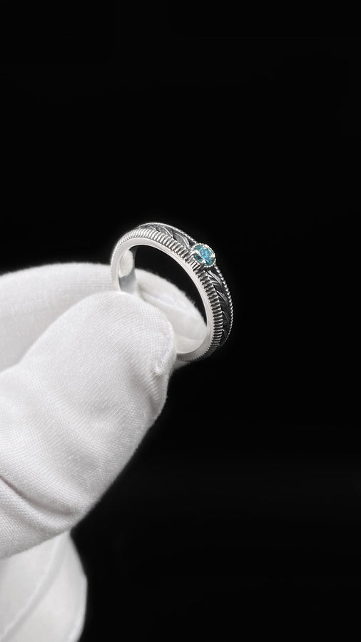 A nature-inspired silver wedding ring featuring raised leaf motifs and a shimmering round gemstone set in the center. The Art Nouveau style is expressed through smooth curves and organic detailing along the band. Ideal for brides or grooms who appreciate delicate plant symbolism, handcrafted jewelry, and an elegant blend of vintage and contemporary design elements in their wedding set. (etsy image id: 6300134508)