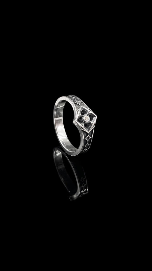 A professional studio photograph of a matching two-piece sterling silver wedding ring set. Both rings feature a prominent, raised Greek-style cross motif in the center, which holds a round, bezel-set white crystal. The interior of the cross arms has a fine, cross-hatched grid texture. Along the sides of the high-polished silver bands are recessed, four-lobed quatrefoil shapes. The rings are presented against a pitch-black background, making the p __etsy:8051335185