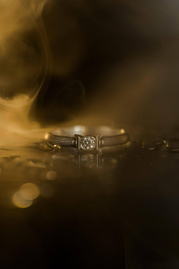 The photograph captures a slim Victorian silver ring with a gemstone framed by sculpted column motifs. Fine linear textures cover the band, giving it a classical, antique appeal. The gemstone sparkles softly, contrasting the darker oxidized grooves. This intricate design suits those who appreciate architectural jewelry, artistic detailing, and meaningful handmade engagement pieces. (etsy image id: 6976743880)