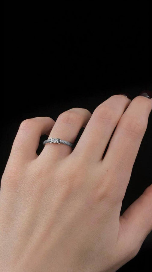The photograph captures a slim Victorian silver ring with a gemstone framed by sculpted column motifs. Fine linear textures cover the band, giving it a classical, antique appeal. The gemstone sparkles softly, contrasting the darker oxidized grooves. This intricate design suits those who appreciate architectural jewelry, artistic detailing, and meaningful handmade engagement pieces. (etsy image id: 6976743880)