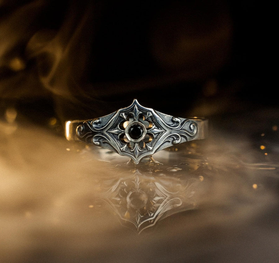 Close-up view of a gothic floral silver ring showcasing a detailed rose-inspired pattern and a polished black gemstone set in the middle. The intricate scrollwork surrounding the stone resembles cathedral tracery, giving the ring an old-world, medieval look. Perfect for engagement, weddings, anniversaries, or collectors of dark romantic jewelry and handcrafted artistic pieces. (etsy image id: 7243100328)