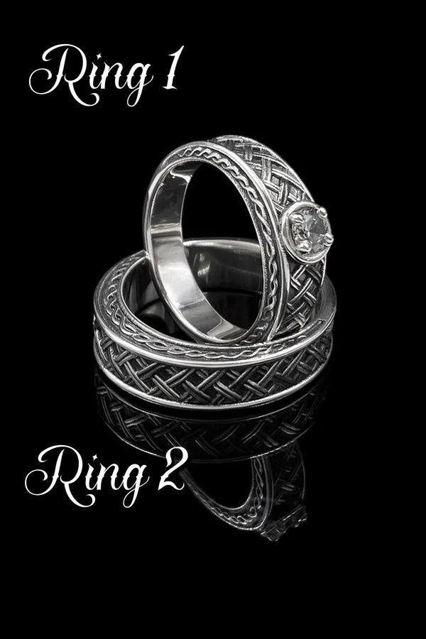 A warm, atmospheric shot of a matching wedding ring set. The engagement ring stands upright, showcasing a round white gemstone in a bezel setting. Lying flat beneath it is a matching wide band without a stone. Both rings share a cohesive design: a central diagonal "basket weave" pattern flanked by twisted rope borders. The silver is oxidized to reveal the intricate texture of the weave.