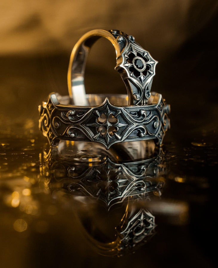 Handmade sterling silver band with an intricate gothic crown motif in the center, framed by swirling ornamental engravings. The deep relief and antique darkened finish evoke historic cathedral carvings. Ideal for customers seeking dark romantic jewelry, gothic accessories, medieval wedding rings, and meaningful silver bands with symbolic architecture-inspired designs. (etsy image id: 7423455351)