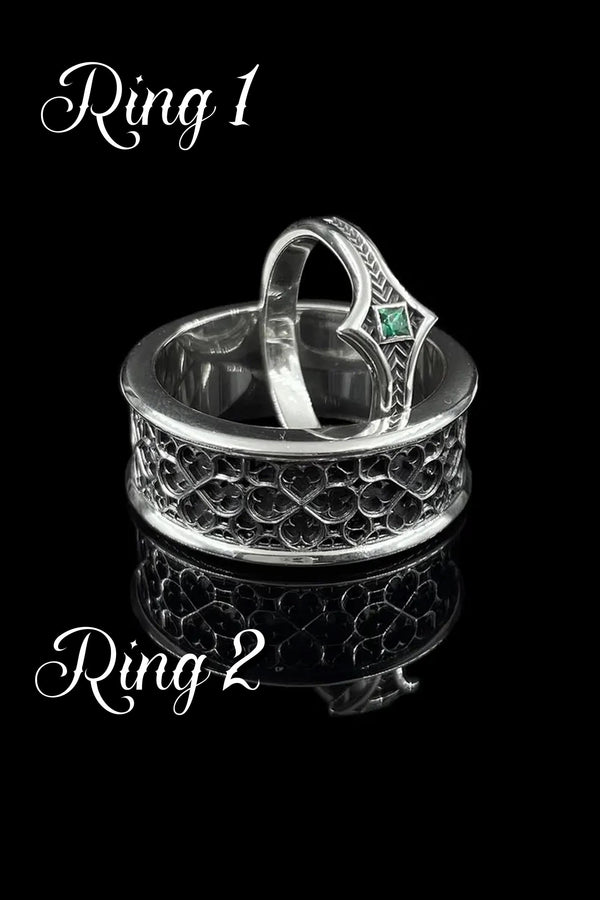 A high-definition shot of a matching two-piece wedding ring set resting on dark velvet. The foreground features a delicate sterling silver ring with a pointed, kite-shaped face holding a square blue gemstone. Standing behind it is a wide, sturdy band with a repeating quatrefoil "clover" pattern. Both rings share a cohesive finish: bright polished silver highlights against a deeply oxidized, matte black background.