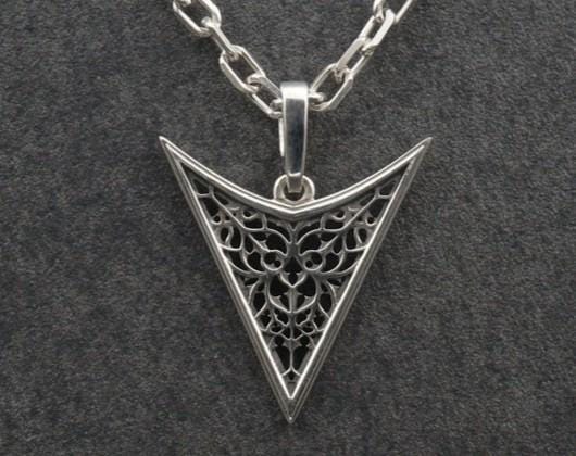 A detailed studio shot of an inverted triangle-shaped pendant hanging from a sturdy chain. The design features a "V" shape frame filled with complex, organic filigree. The inner pattern resembles branching roots, veins, or the "Flamboyant" style of late Gothic window tracery. The raised silver lines are polished bright, contrasting with the matte black oxidation in the negative spaces. (etsy image id: 7496362357)