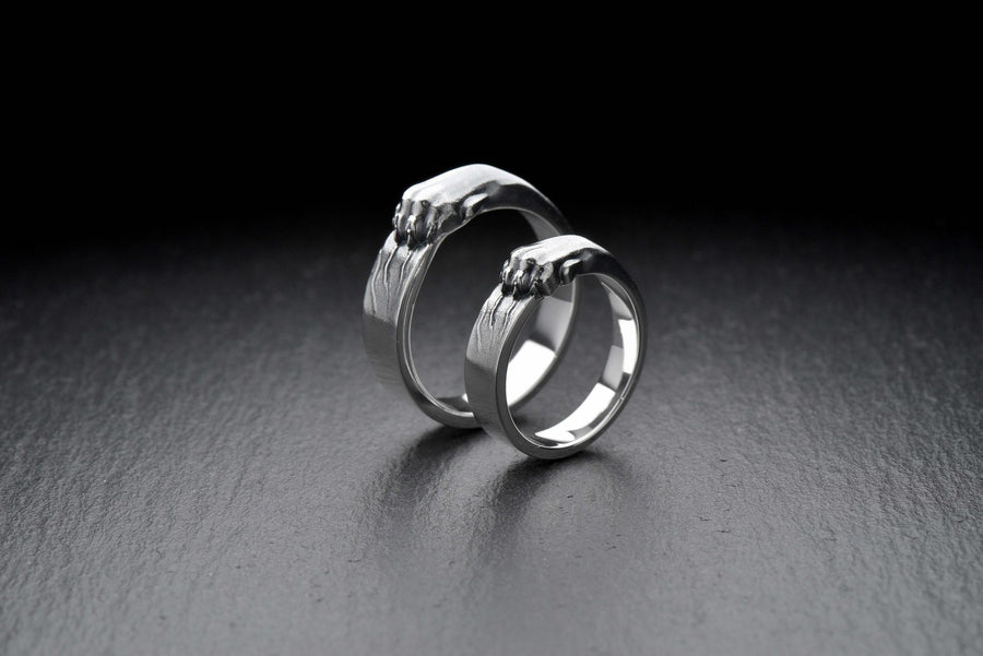 A pair of gothic sterling silver wedding rings featuring sculpted claw details that wrap organically around each band. The dramatic design blends polished metal with textured claw surfaces, creating a symbolic representation of unity and strength. Ideal for alternative couples who appreciate bold artisan jewelry with dark, meaningful aesthetics and handcrafted quality suitable for weddings or promise rings.