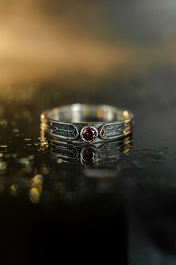 This gothic sterling silver ring features a vivid red garnet set in a detailed medieval-inspired band with darkened textures and graceful, pointed motifs. Designed for lovers of fantasy, gothic fashion, and artisan jewelry, it offers an elegant yet dramatic look. Perfect as a unique wedding band, engagement ring, or statement piece for anyone drawn to symbolic and timeless gothic style. (etsy image id: 7425901470)