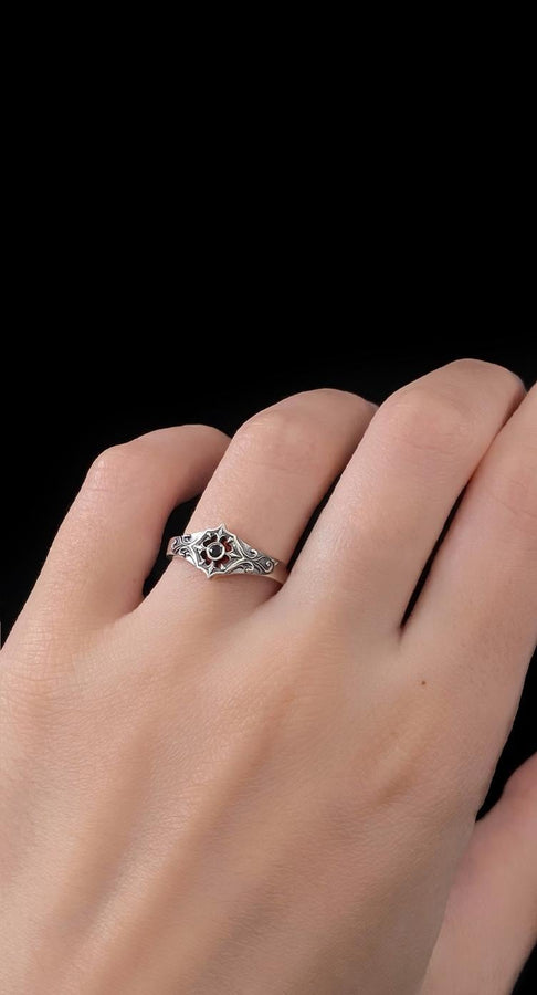Close-up view of a gothic floral silver ring showcasing a detailed rose-inspired pattern and a polished black gemstone set in the middle. The intricate scrollwork surrounding the stone resembles cathedral tracery, giving the ring an old-world, medieval look. Perfect for engagement, weddings, anniversaries, or collectors of dark romantic jewelry and handcrafted artistic pieces. (etsy image id: 7243100328)