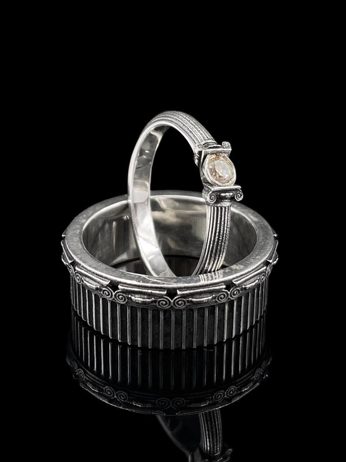 A polished sterling silver wedding band inspired by historical Greek architecture, featuring full-length vertical column lines and detailed Ionic scrollwork. The ring’s reflective interior contrasts with the textured exterior, emphasizing craftsmanship and depth. This Art Deco–style temple band is ideal for those who love structural jewelry rooted in ancient culture and timeless design. (etsy image id: 7193919287)