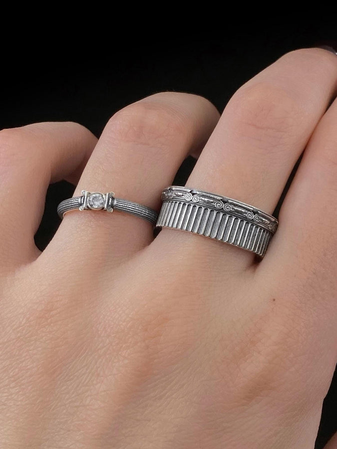 A polished sterling silver wedding band inspired by historical Greek architecture, featuring full-length vertical column lines and detailed Ionic scrollwork. The ring’s reflective interior contrasts with the textured exterior, emphasizing craftsmanship and depth. This Art Deco–style temple band is ideal for those who love structural jewelry rooted in ancient culture and timeless design. (etsy image id: 7193919287)