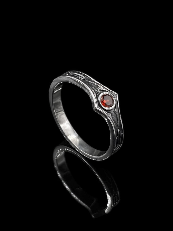 A cinematic close-up of a sterling silver ring with a distinct "V" shaped or "Lance Tip" contour. The focal point is a bezel-set, round gemstone with a deep amber-orange hue (Citrine or Madeira Citrine). The shoulders of the band feature horizontal grooves that taper toward the center, resembling the shaft of a spear or the fletching of an arrow. The metal is polished but features dark oxidation in the grooves for contrast. (etsy image id: 7489049399)