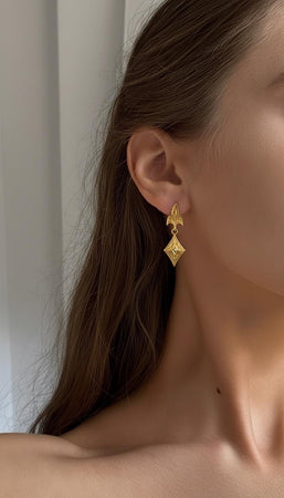 The Fleur-de-Lis earrings are reimagined in 14k Yellow Gold. The transformation makes them look like French royal regalia from the court of Versailles. The gold emphasizes the floral nature of the design, making the vines look like sunlit garden trellises. This version feels opulent, classic, and incredibly expensive, suitable for a luxury gift. (etsy image id: 7218769544)