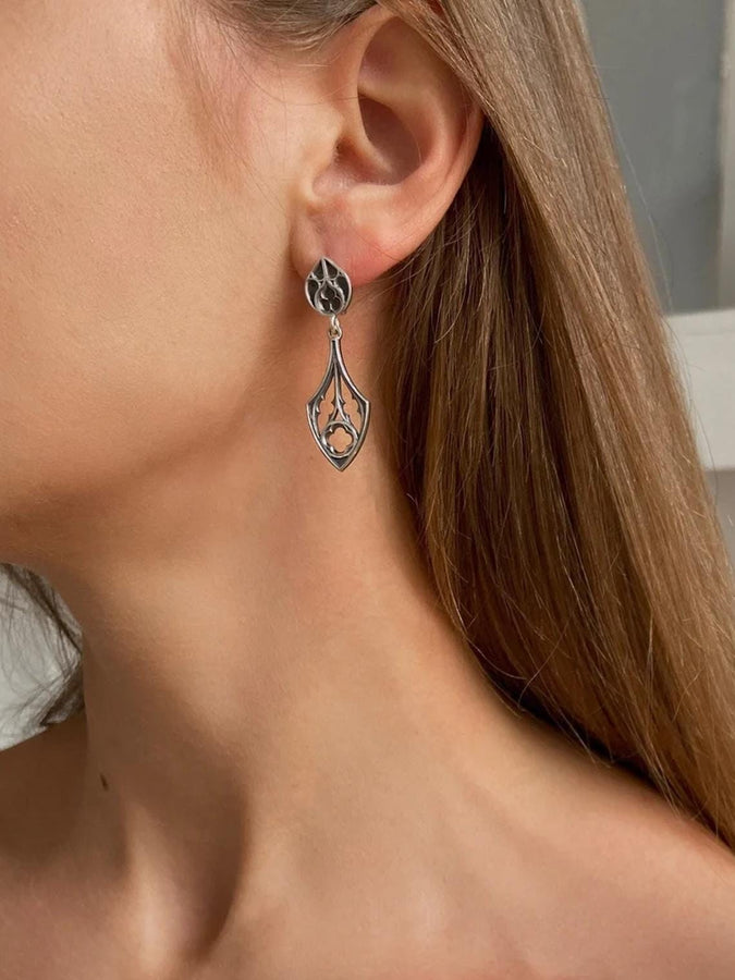 Embrace the dark appeal of gothic fashion with our Sterling Gothic Earrings. Each pair is exquisitely crafted in a gothic style, bringing a touch of mystery and romance to your look. An ideal choice for those who appreciate dark shades of elegance. The image highlights the high-contrast finish of the 925 sterling silver. The "relief" casting gives the tracery lines a three-dimensional quality, mimicking carved stone. (etsy image id: 6150699379)