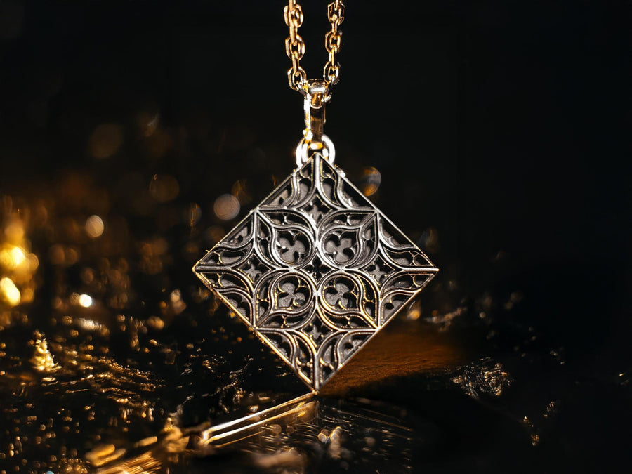 A detailed studio shot of a diamond-shaped (lozenge) sterling silver pendant hanging vertically. The design features intricate "curvilinear" Gothic tracery—four teardrop shapes meeting in the center to form a cross or quatrefoil. The raised lines are polished bright silver, while the negative space behind them is heavily oxidized to a matte black, creating a high-contrast architectural look. (etsy image id: 7494090955)